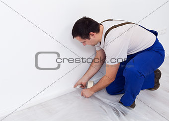 Painter worker preparing the room - laying protection film