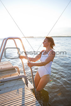 Attractive woman climbing ladder to pier