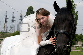 fiancee in a wedding dress astride on a horse