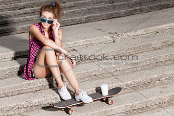 beautiful sexy lady in jeans shorts with skateboard at stone sta