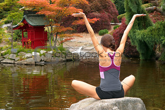 Woman Reaches for the Sky on Rock in Yoga Pond
