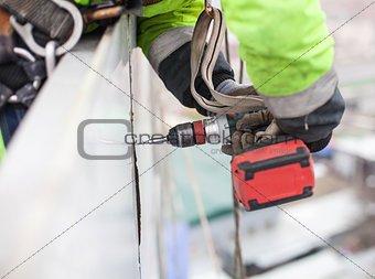 Closeup of industrial climber with screwdriver on metal construction