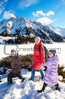 Family (mother with two children) take a walk on winter mountain