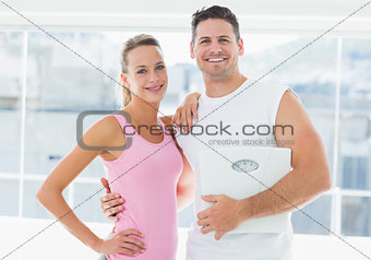 Portrait of a fit couple holding weighing scale