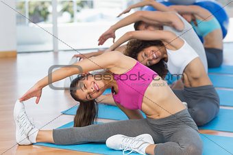 Sporty people doing stretching exercises in fitness studio