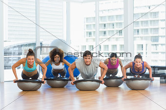 Smiling people doing push ups in fitness studio