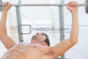 Shirtless fit man lifting the barbell bench press