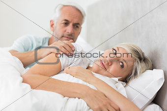 Woman ignoring mature man in bed