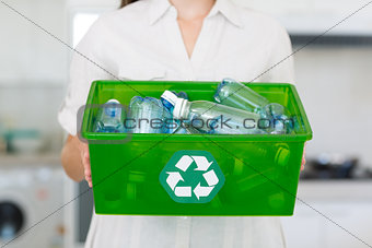 Mid section of woman carrying box with recycling symbol