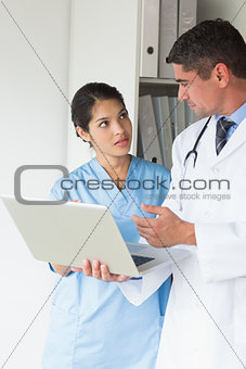 Doctor and nurse discussing over laptop