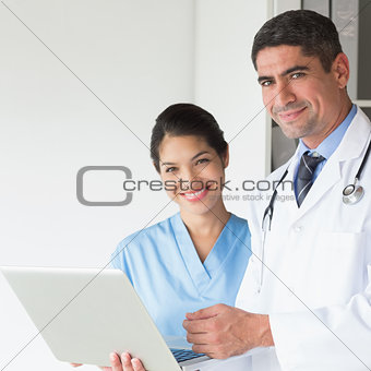 Confident doctor and nurse using laptop