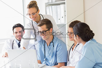 Smiling doctors and nurses discussing over laptop