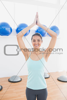 Beautiful woman with joined hands in fitness studio