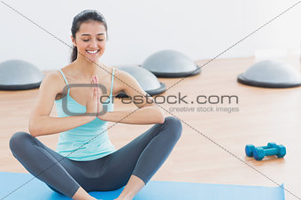 Beautiful sporty woman with joined hands in fitness studio