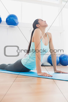 Fit woman doing the cobra pose in fitness studio