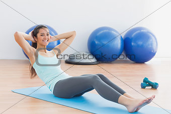 Smiling woman doing sit ups in fitness studio