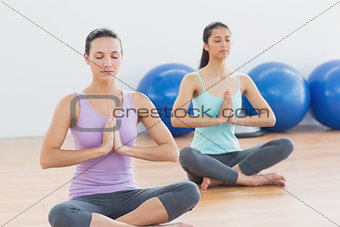 Two sporty women with joined hands in fitness studio