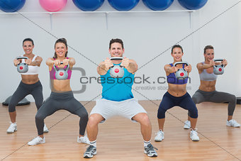Class and instructor exercising with kettlebells in gym