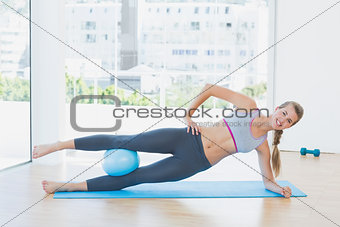 Sporty woman exercising with ball in fitness studio