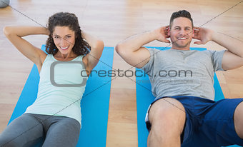 Smiling couple doing sit ups