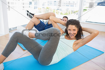 Couple doing sit ups in fitness studio