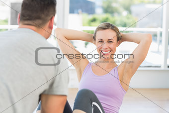 Trainer helping woman doing sit ups
