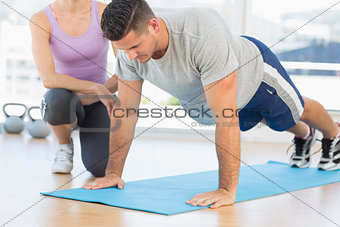 Trainer assisting man with push ups