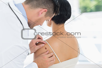 Doctor examining mole on back of woman