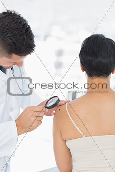 Dermatologist examining mole on woman