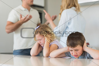 Children covering ears while parents arguing