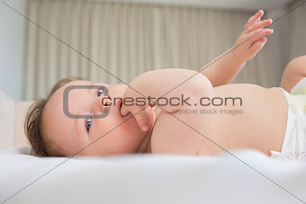 Baby with finger in mouth lying on crib