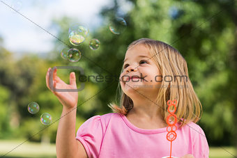 Girl looking at soap bubbles at park