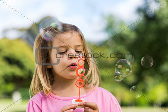 Cute girl blowing soap bubbles at park