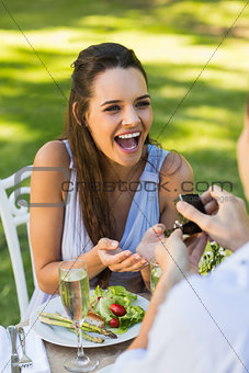 Man proposing cheerful woman at an outdoor café