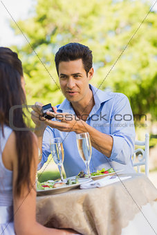 Man proposing a woman at an outdoor café