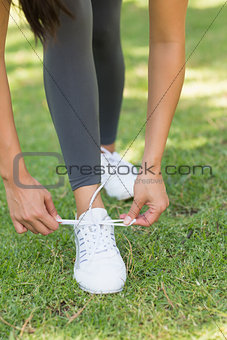 Low section of woman tying shoe lace at park