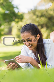 Smiling woman text messaging while relaxing in park
