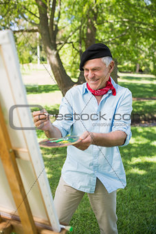 Happy mature man painting in park