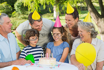 Extended family wearing party hats at birthday celebration in park
