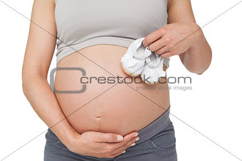 Pregnant woman holding baby shoes over bump