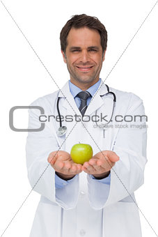 Smiling doctor showing apple to camera