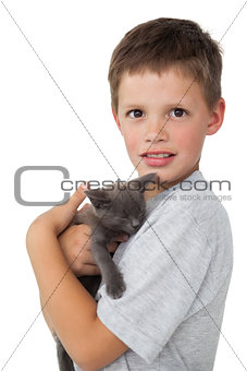 Little boy holding grey kitten smiling at camera