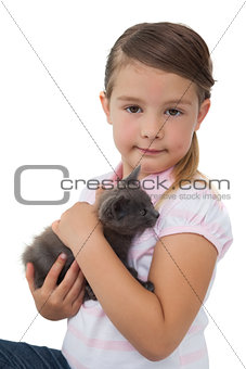 Cute girl holding grey kitten smiling at camera