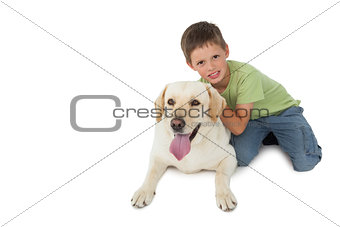 Cute little boy kneeling with his labrador smiling at camera