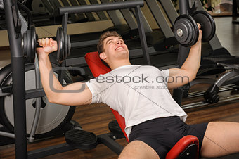 Young man doing Dumbbell Incline Bench Press workout in gym