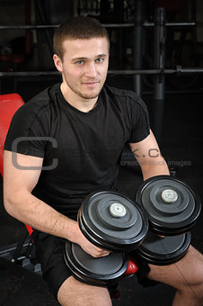young man sits after workout in gym