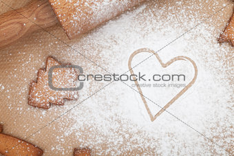 Rolling pin with flour and cookies on cooking paper