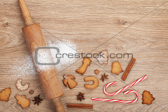 Rolling pin with flour, spices and cookies on wooden table