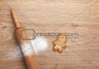 Rolling pin with flour and gingerbread cookie on wooden table