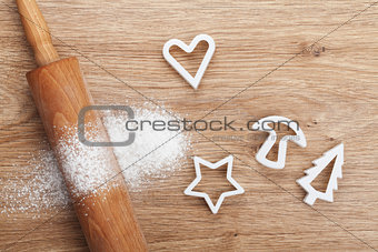 Rolling pin with flour and cookie cutters on wooden table